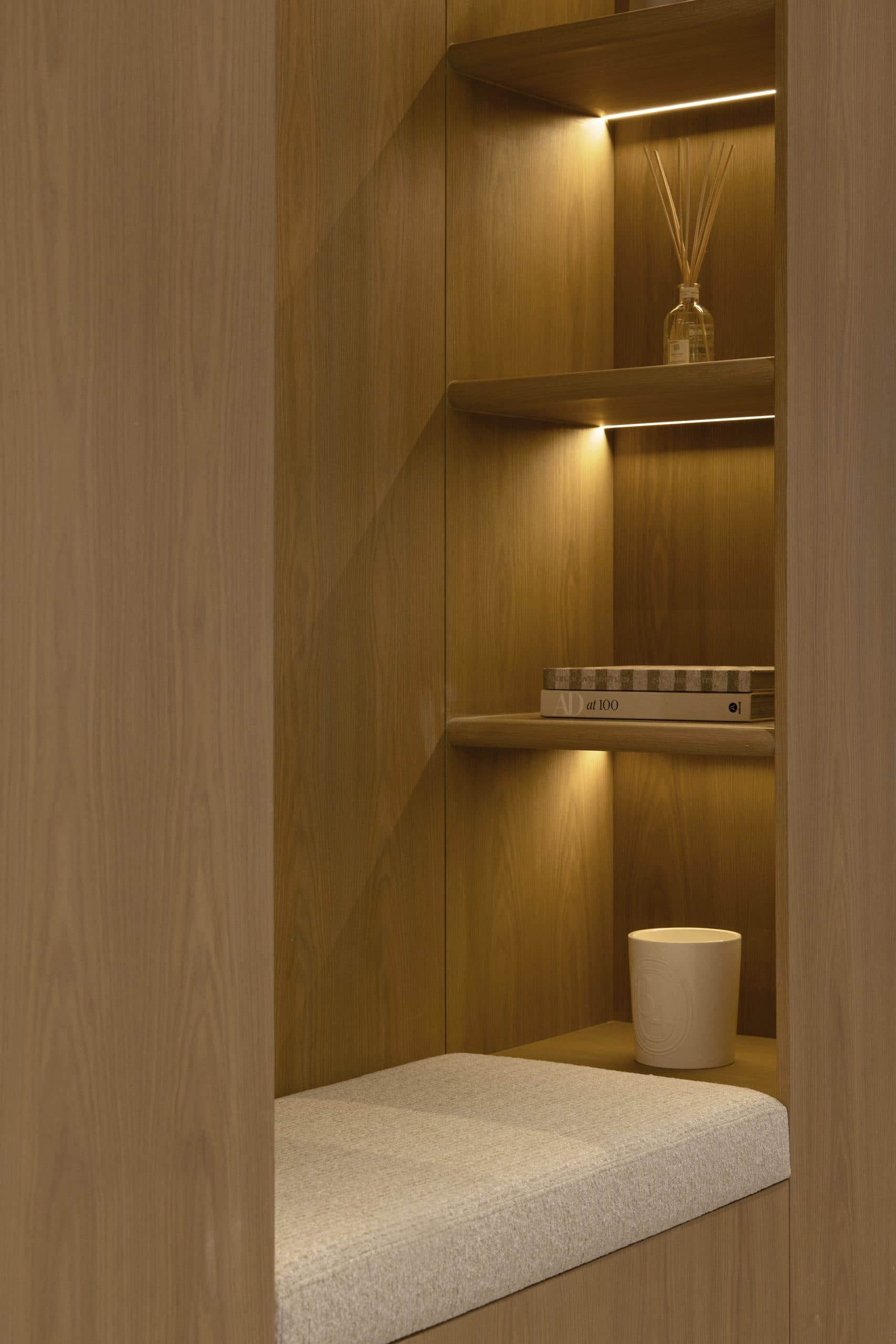 Lit oak display niche with a built-in bench in a panelled hallway