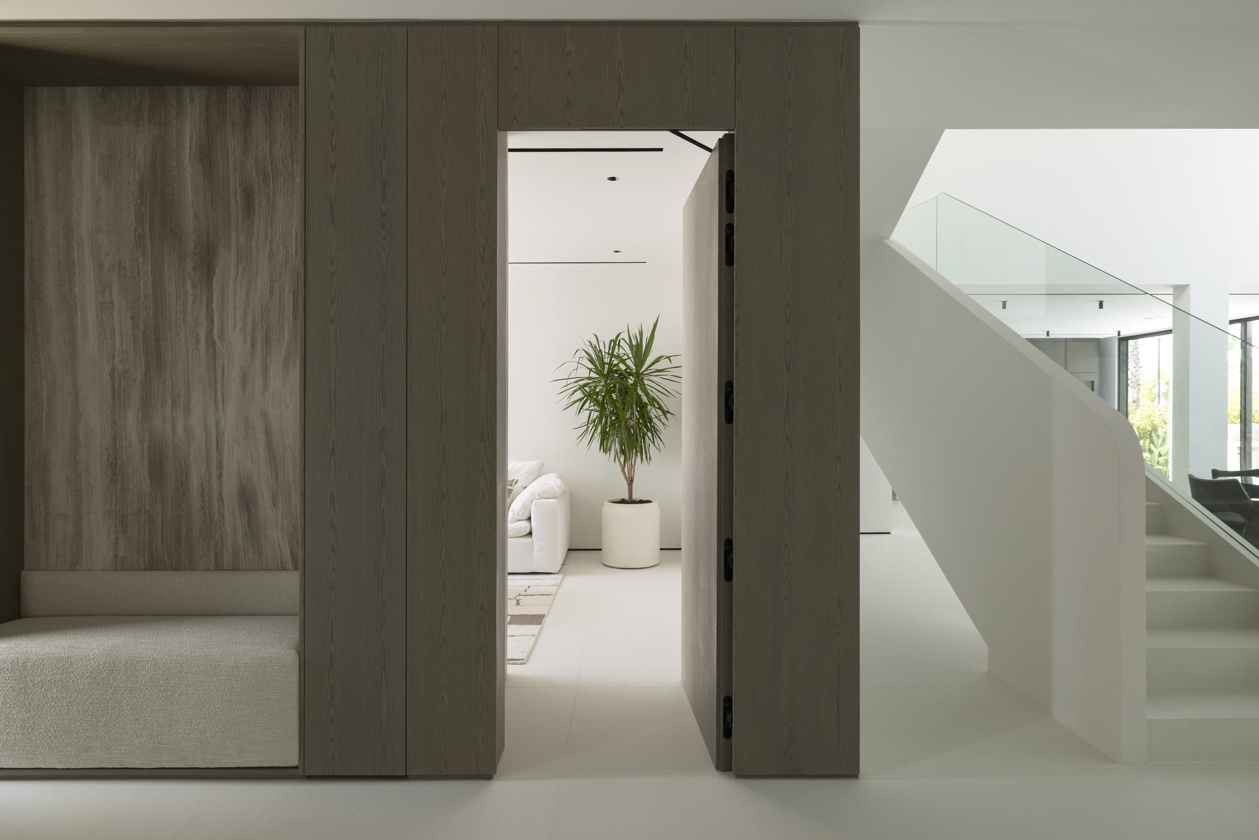 Oak-clad volume framing a doorway beside a floating staircase